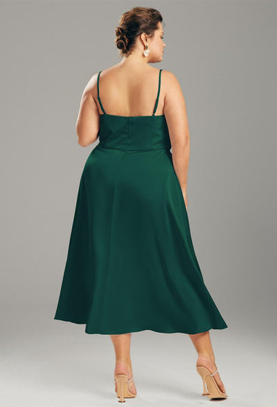 The back view of a plus size woman in a green midi dress, perfect as a bridesmaid dress option for Bergamot Bridal shops in London, wearing the Renee - Satin Charmeuse Bridesmaid Dress - Off the Rack.