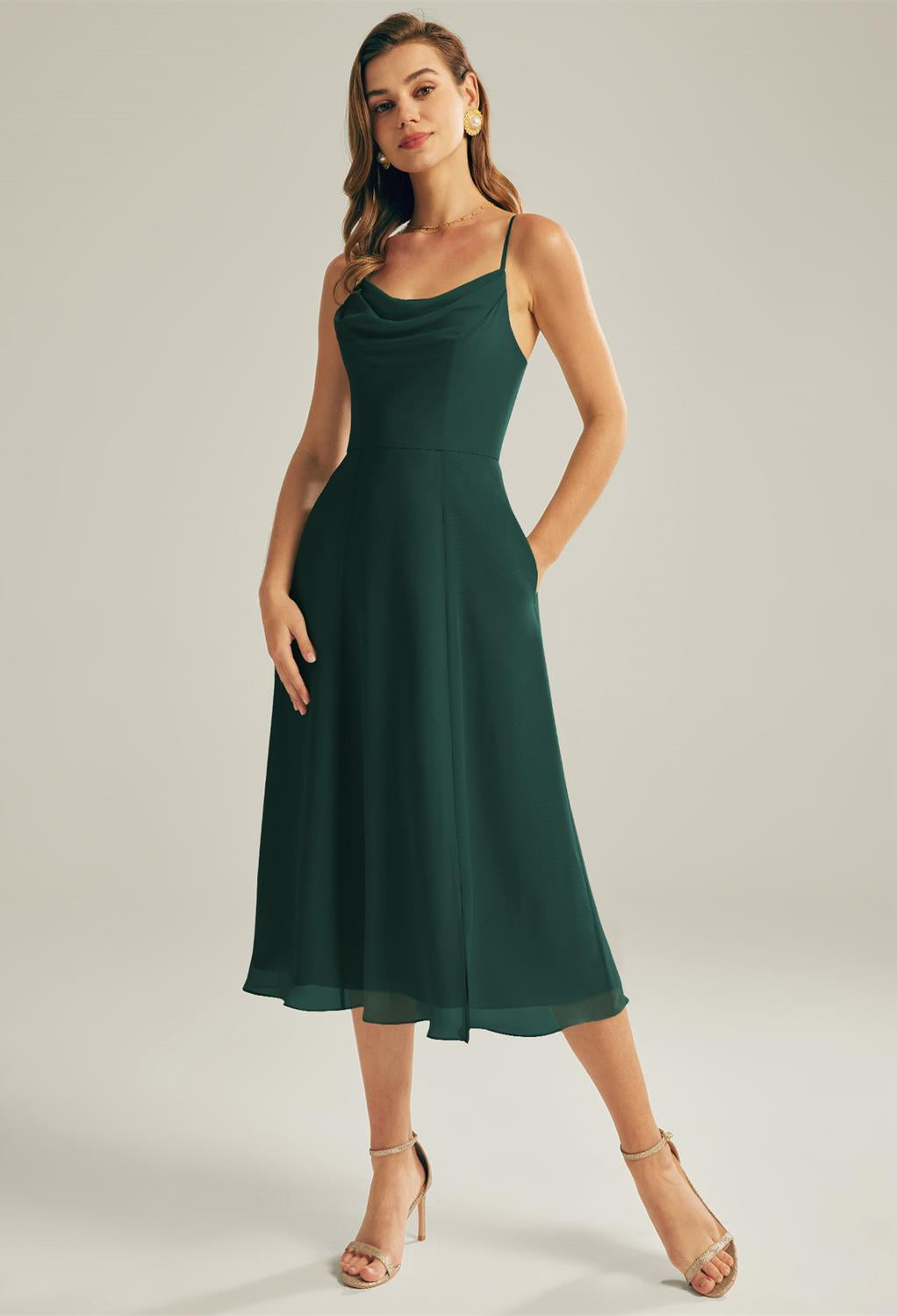 A woman in a Maribel - Chiffon Bridesmaid Dress - Off the Rack by Bergamot Bridal in a green color.