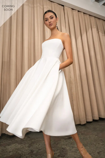 The model is showcasing a stunning Carrie - Jenny Yoo Little White Dress by Bergamot Bridal.