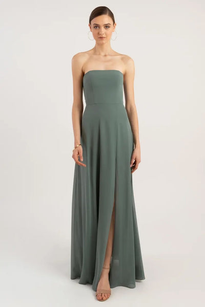 Woman in a sleek, strapless green chiffon Essie bridesmaid dress by Jenny Yoo with a boned bodice and a thigh-high slit from Bergamot Bridal.