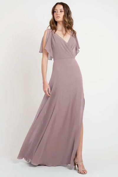 A woman modeling a beautiful mauve evening gown with flutter sleeves and a v-neckline, Hayes - Bridesmaid Dress by Jenny Yoo from Bergamot Bridal.
