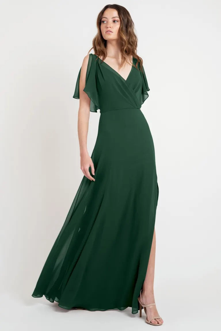 A woman in a Hayes - Bridesmaid Dress by Jenny Yoo, store sample size, with flutter sleeves and a flowing skirt from Bergamot Bridal.