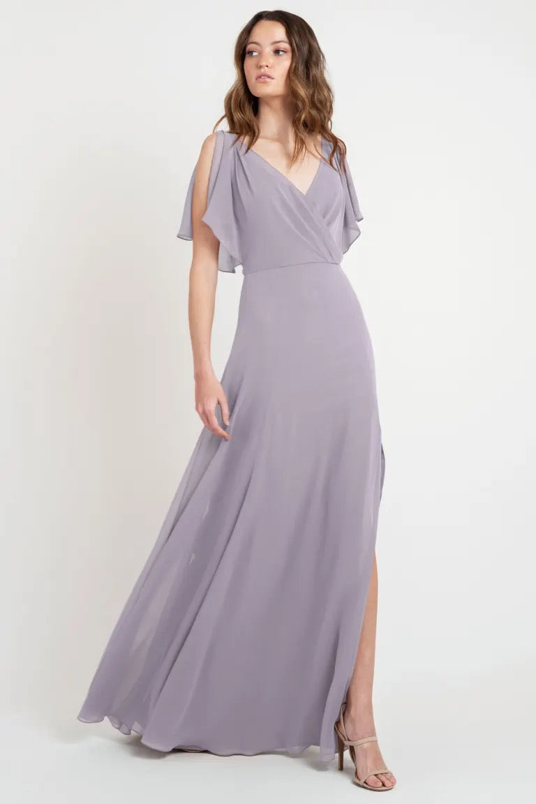 Woman modeling a beautiful dress, specifically a size 24 flowy lavender evening gown with flutter sleeves and a v-neckline, Hayes - Bridesmaid Dress by Jenny Yoo from Bergamot Bridal.