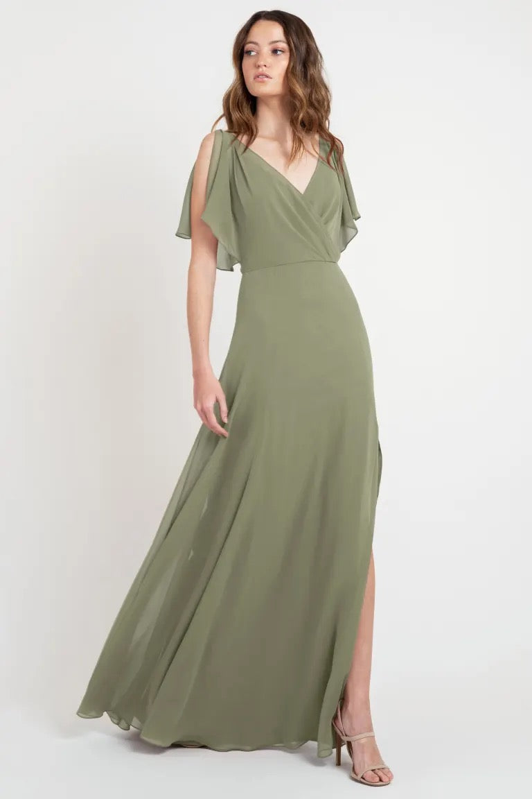 Woman posing in a beautiful, flowing olive green Hayes - Bridesmaid Dress by Jenny Yoo with flutter sleeves and a v-neckline from Bergamot Bridal.