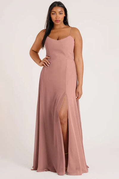 A woman in a luxe chiffon, Kiara - Bridesmaid Dress by Jenny Yoo featuring an A-line skirt with a high slit from Bergamot Bridal.