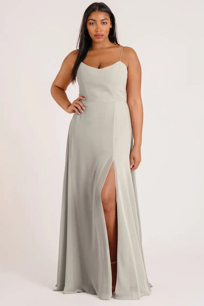 Woman modeling a light gray Kiara - Bridesmaid Dress by Jenny Yoo with a luxe chiffon A-line skirt and a thigh-high slit from Bergamot Bridal.