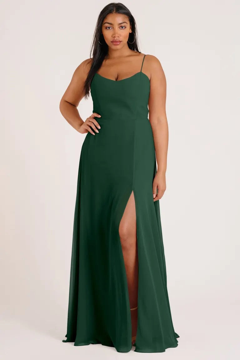 A person in a green Kiara - Bridesmaid Dress by Jenny Yoo with a thigh-high slit from Bergamot Bridal.