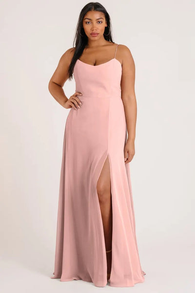 Woman posing in a luxe chiffon, Kiara - Bridesmaid Dress by Jenny Yoo with a thigh-high side slit from Bergamot Bridal.