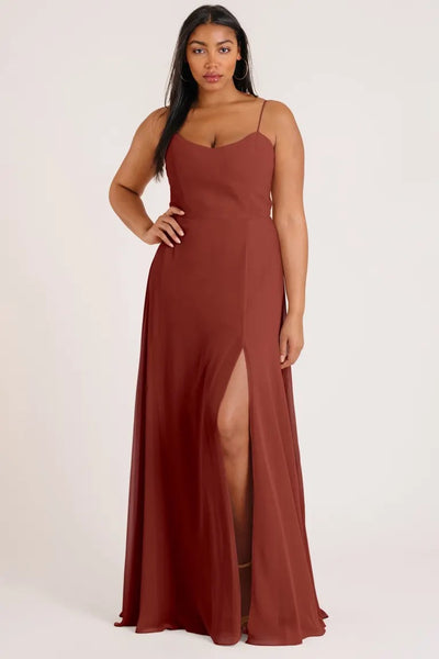 A woman standing in a full-length pose wearing an elegant Bridesmaid Dress by Jenny Yoo in luxe chiffon, with a slit up the leg and an A-line skirt from Bergamot Bridal.