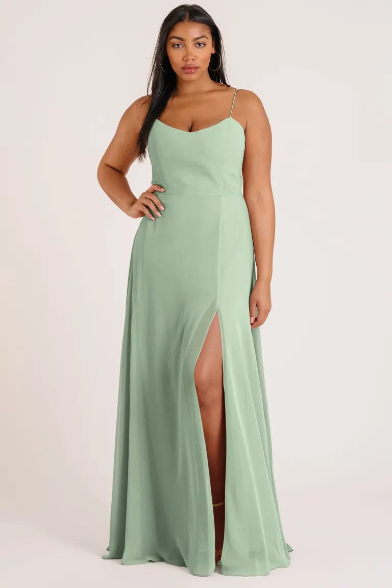 A woman wearing a luxe chiffon Kiara bridesmaid dress by Jenny Yoo with an A-line skirt and a thigh-high slit from Bergamot Bridal.