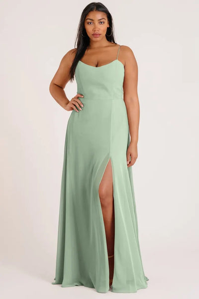 A woman wearing a luxe chiffon Kiara bridesmaid dress by Jenny Yoo with an A-line skirt and a thigh-high slit from Bergamot Bridal.