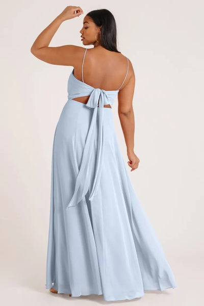Woman in a luxe chiffon Kiara - Bridesmaid Dress by Jenny Yoo with an open back and bow detail standing with her hand on her head from Bergamot Bridal.