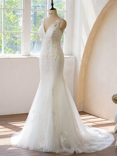 An elegant Illusion Back Fit and Flare With Applique wedding dress from Bergamot Bridal, displayed in a sunlit room.