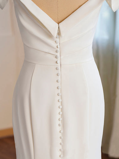 Close-up of a Crepe Off-the-shoulder Pleated Fit And Flare Bridal Gown from Bergamot Bridal in London Ontario, featuring a detailed button back and a v-shaped waistline on a mannequin.