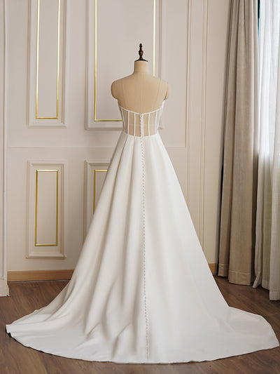 A Modern Satin A-line Wedding Dress with Slit by Bergamot Bridal, on a mannequin in a bridal shop.