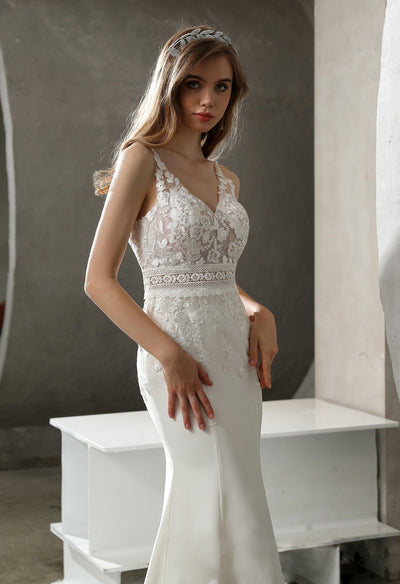 A woman in an elegant bridal gown with floral lace posing indoors.
Product: Crepe and Lace Fit and Flare Dress with Illusion Scalloped Train
Brand: Bergamot Bridal