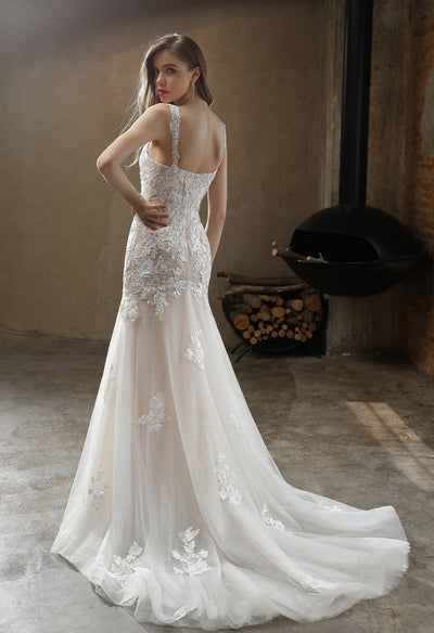A woman in a Bergamot Bridal square neckline with lace straps mermaid wedding gown poses with her back to the camera, showcasing the dress's intricate low back design and flowing train.