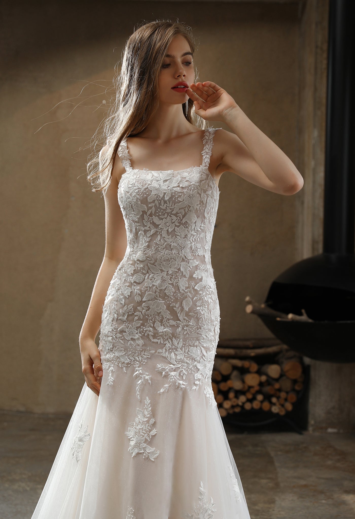 A bride in a Square Neckline with Lace Straps Mermaid Wedding Gown by Bergamot Bridal poses thoughtfully.