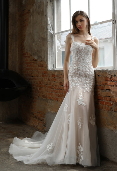 Woman in an elegant Bergamot Bridal Square Neckline with Lace Straps Mermaid Wedding Gown standing beside a window in a room with industrial decor.