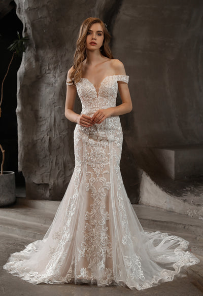 A woman in an elegant off-the-shoulder Bergamot Bridal wedding dress with lace accents.