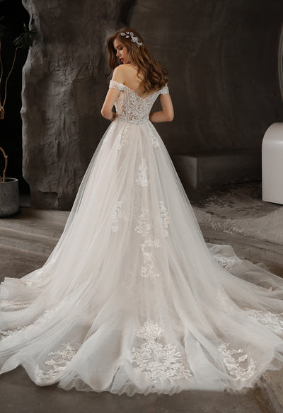 A woman in a Bergamot Bridal Gorgeous Lace Fit and Flare Bridal Gown with Detachable Train in an elegant indoor setting.