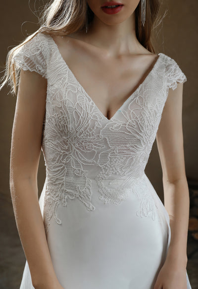 Close-up of a woman in a Bergamot Bridal Crepe Sheath Wedding Dress with Lace Cap Sleeves with Detachable Train.