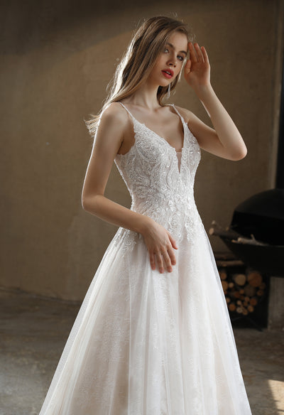 A person in a white Bergamot Bridal Beaded A-Line Wedding Dress with Spaghetti Straps is posing in a room.