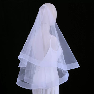 A mannequin adorned in a White Horsehair Trim Bridal Veil and gown from Bergamot Bridal, one of the revered bridal shops in London, set against a black background.