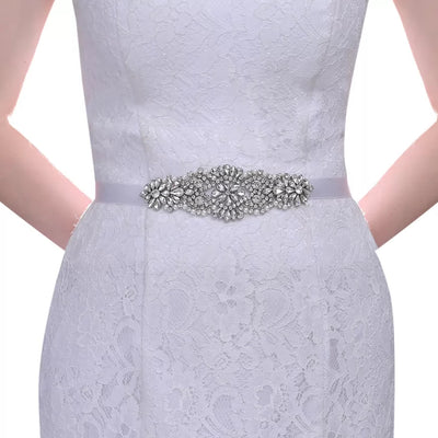 A woman wearing a white lace dress with a Glittering Rhinestones Pearl Bridal Sash from Bergamot Bridal is shopping at one of the bridal shops in London Ontario.