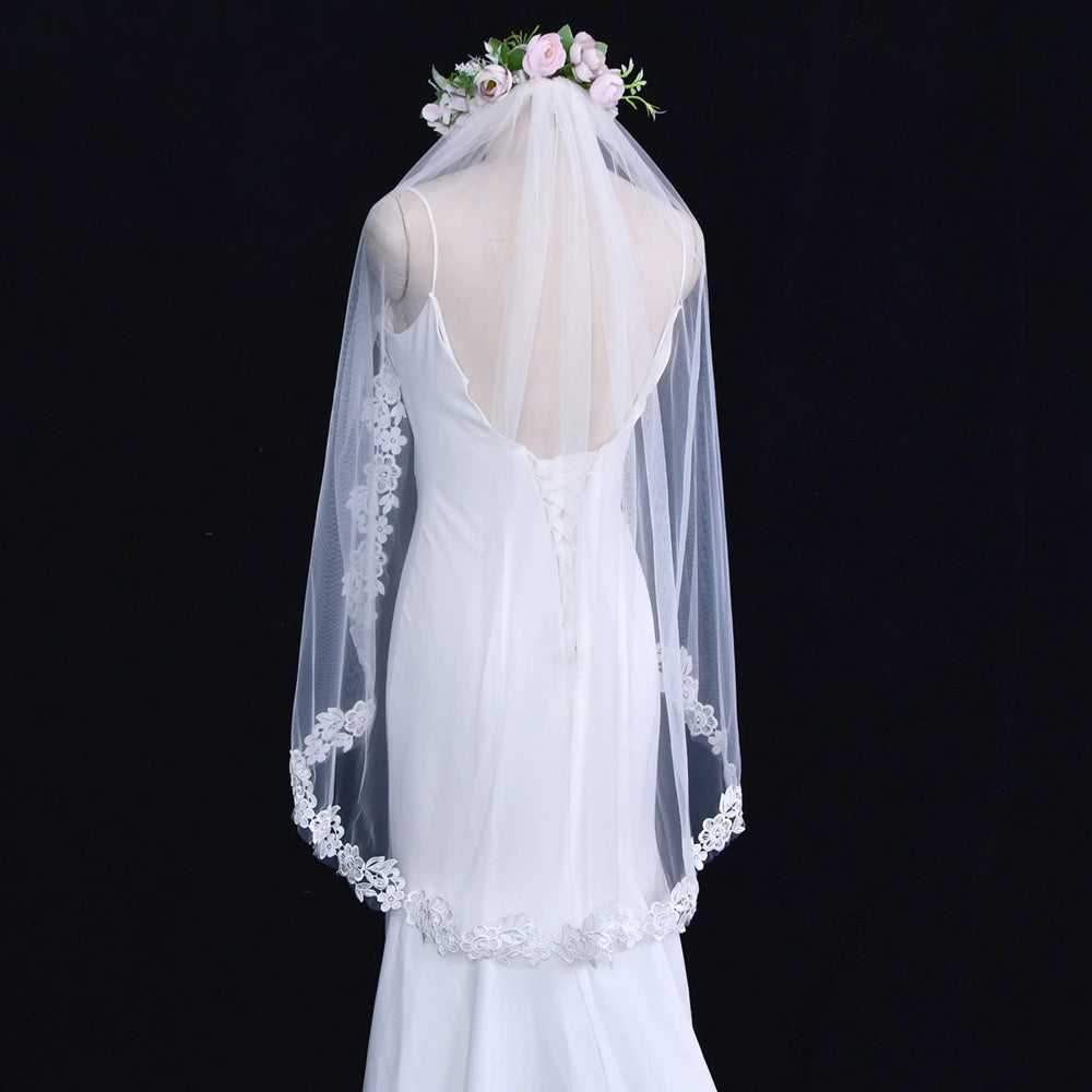 A mannequin showcasing a Bergamot Bridal boho style embroidered floral lace edged fingertip length veil, displayed against a black background.