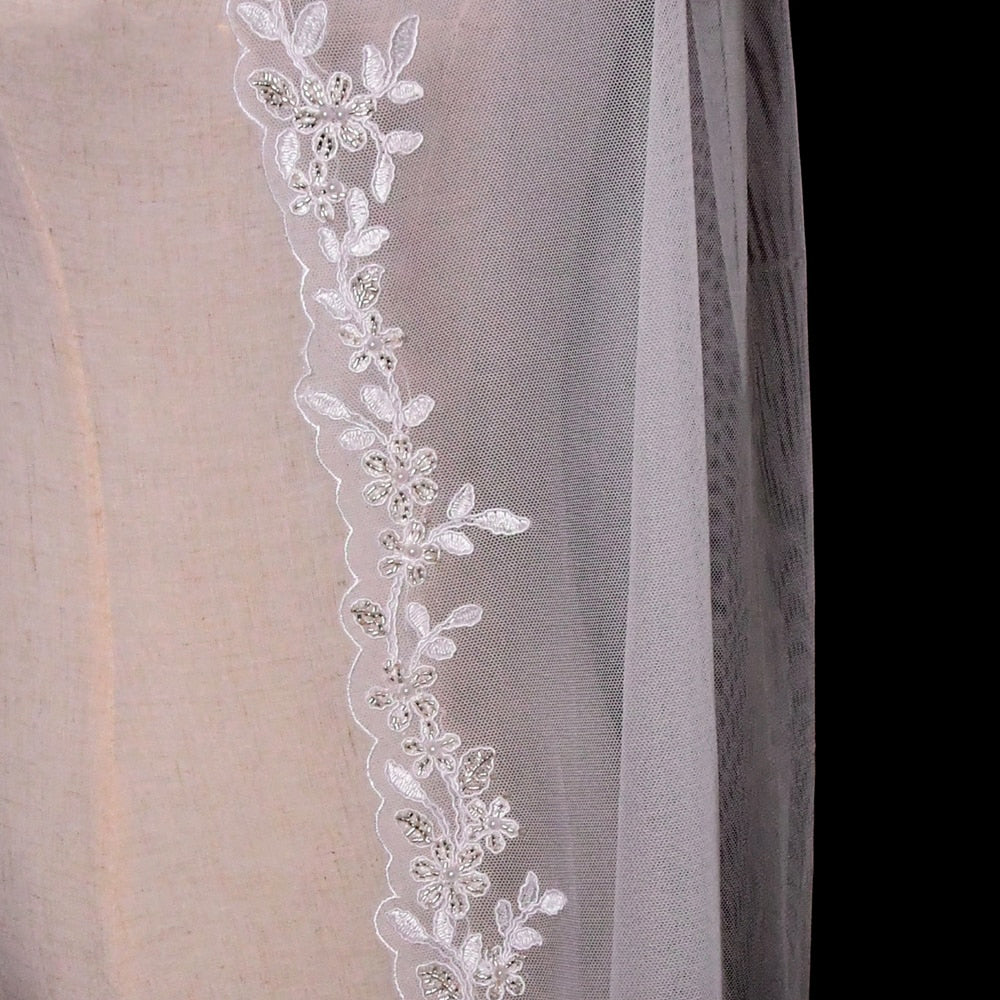 Close-up of a Bergamot Bridal embroidered lace edged fingertip length bridal veil often seen in wedding dresses, highlighting detailed floral embroidery.
