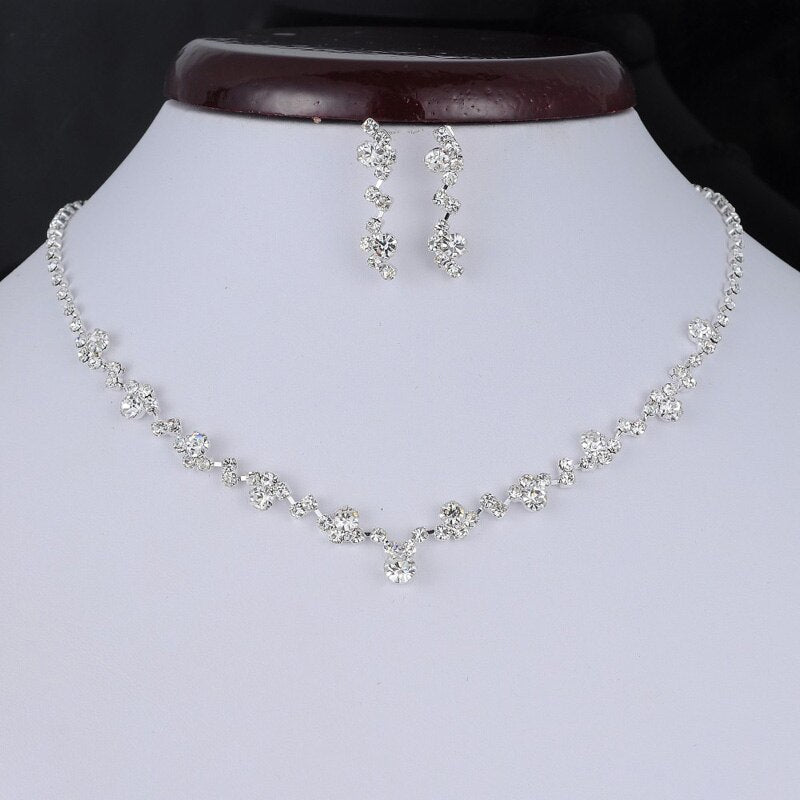 A sparkling Bergamot Bridal crystal necklace and earring set displayed on a black mannequin bust, perfect for complementing wedding dresses from bridal shops in London, Ontario.