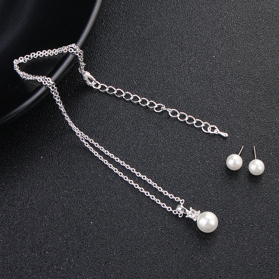 Bergamot Bridal's pearl pendant necklace and stud earring set, ideal for bridal shops, accompanied by a pair of pearl earrings, displayed on a black background.