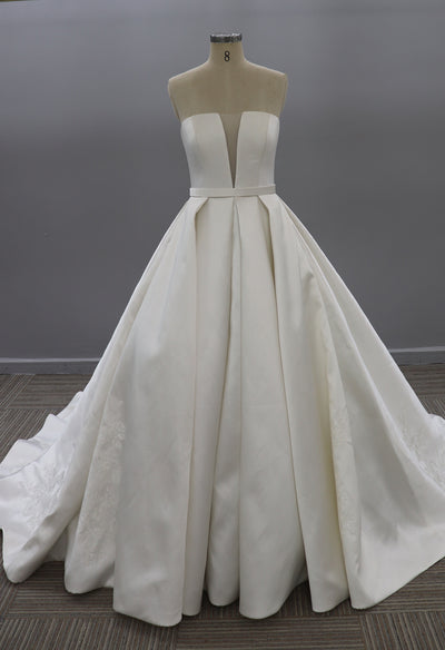 A white Modern Strapless Satin Ballgown With Illusion Plunge neckline by Bergamot Bridal on a mannequin at a bridal shop in London.