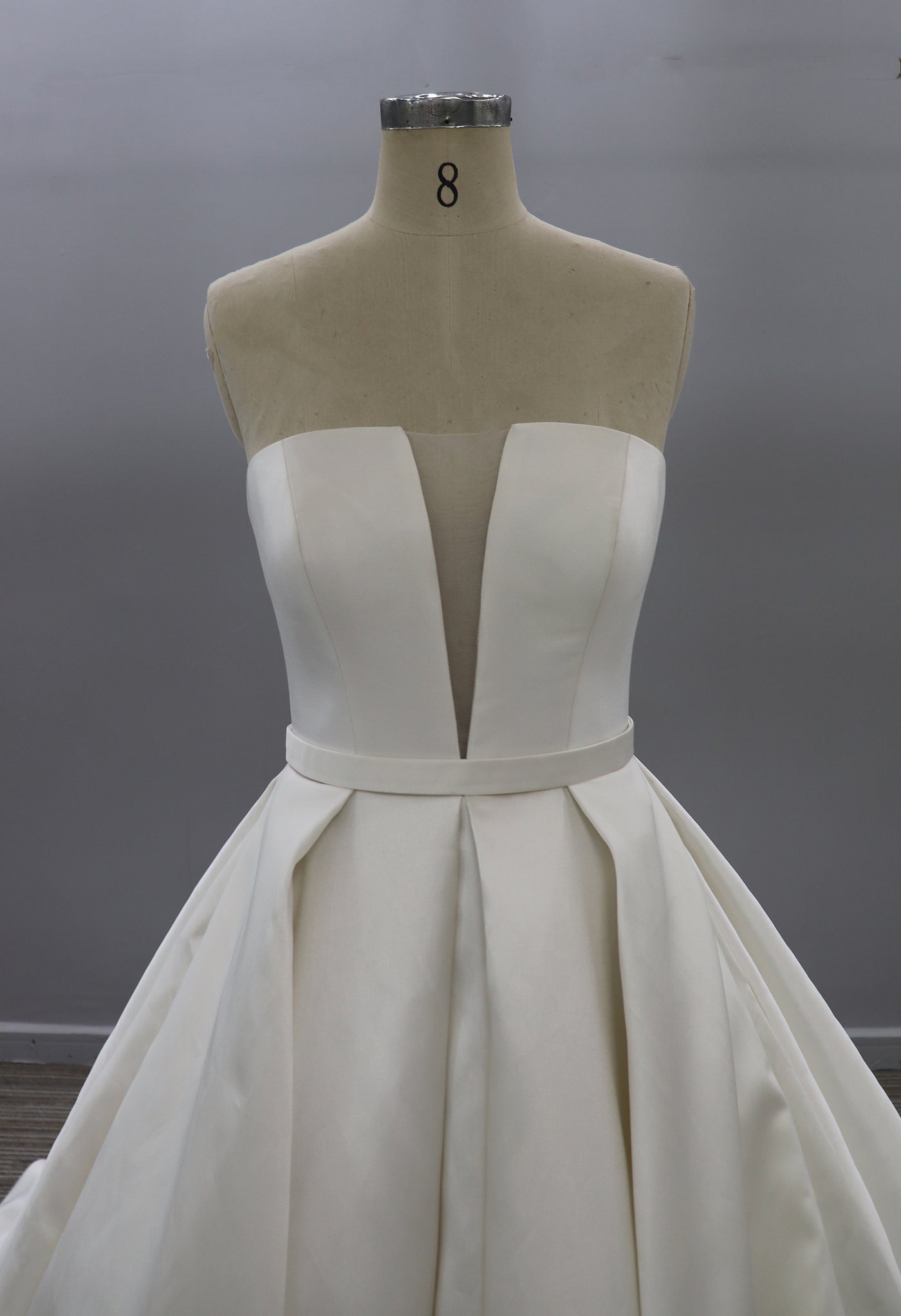 A Modern Strapless Satin Ballgown With Illusion Plunge neckline from Bergamot Bridal on a mannequin at a bridal shop in London.