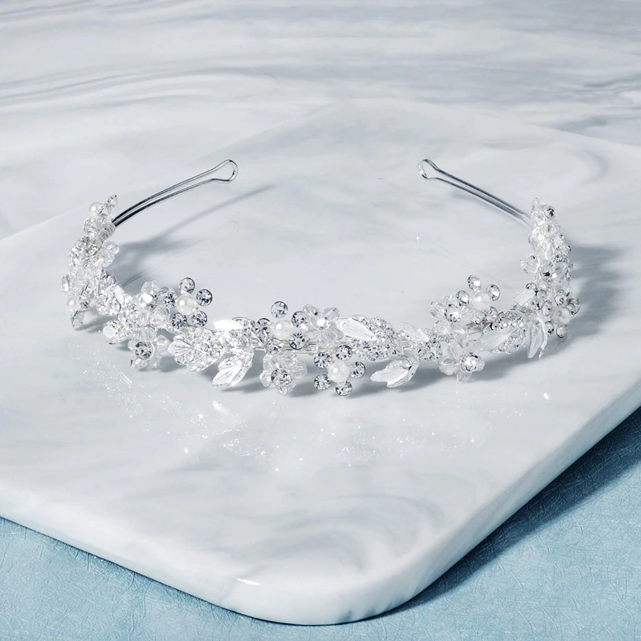 A Floral Crystal Bridal Hairband Wreath by Bergamot Bridal on a marble table in bridal shops.