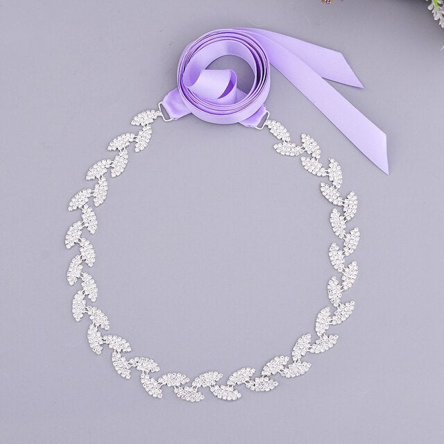 Silver leaf crystal bridal belt sash by Bergamot Bridal with a long lilac crystals ribbon on a gray background.