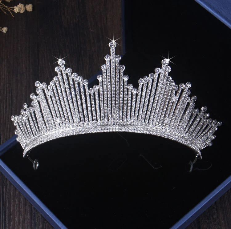 A sparkling silver tiara adorned with crystals and star designs, ideal for Bergamot Bridal shops, displayed in an open blue box on a dark wooden surface.