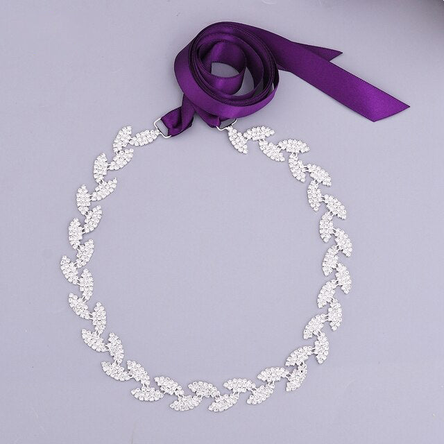 Silver leaf crystal bridal belt sash by Bergamot Bridal with a purple crystals ribbon on a light gray background.