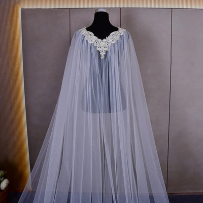 A long, flowing pale blue Bergamot Bridal cathedral length cape with beaded detail on a mannequin against a wooden panel backdrop, perfect for bridal shops in London, Ontario.
