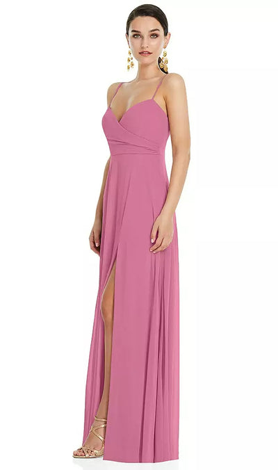 A woman in a pink adjustable strap wrap bodice maxi bridesmaid dress with front slit, Style LB036 by Bergamot Bridal, is standing and looking forward.