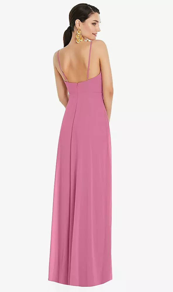 A woman gracefully faces away, wearing the Bergamot Bridal Adjustable Strap Wrap Bodice Maxi Bridesmaid Dress in lux chiffon with a surplice bodice and front slit, complemented by gold earrings.