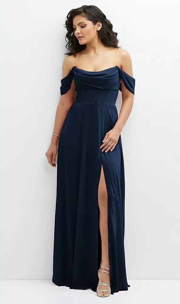 Dressed in a Chiffon Corset Maxi Dress with Removable Off-the-Shoulder Swags Bridesmaid Dress - Style 1577 by Bergamot Bridal, paired with silver high heels, a person stands elegantly against a white background, showcasing the breathtaking design.