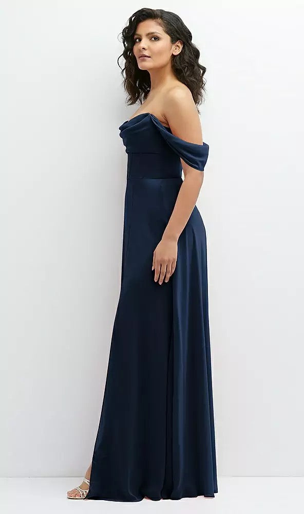 A woman elegantly poses against a white background, wearing a breathtaking Chiffon Corset Maxi Dress by Bergamot Bridal. This navy blue gown, featuring removable off-the-shoulder swags, is the perfect choice for any bridal party ensemble.