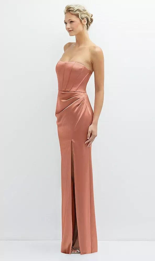 A woman wearing the Strapless Topstitched Corset Satin Maxi Dress with a Draped Column Skirt by Bergamot Bridal - Dessy Style 6888, poses elegantly against a plain background.