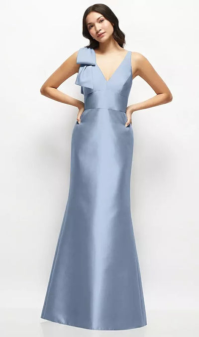 A woman poses against a white background in the floor-length Deep V-back Satin Trumpet Bridesmaid Dress by Bergamot Bridal. This light blue, Dessy Style D863 gown is elegantly finished with a handcrafted bow cascading from the left shoulder.