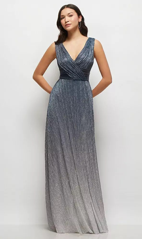 A woman stands against a plain background, elegantly dressed in the Bergamot Bridal Draped V-Neck Ombre Pleated Metallic Maxi Bridesmaid Dress - Style 6895OMB by Dessy, featuring a chic shirred waist and a dramatic deep V-back.