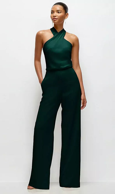 Someone is wearing the Bergamot Bridal After Six Lore Style 6907, a dark green pleated halter blouson crepe wedding jumpsuit with wide legs and a self-tie bow, against a plain white background.