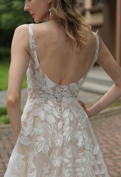 The back view of a woman in Bergamot Bridal's Luxurious Floral Lace A-Line Wedding Dress With Sheer Train in a bridal shop.