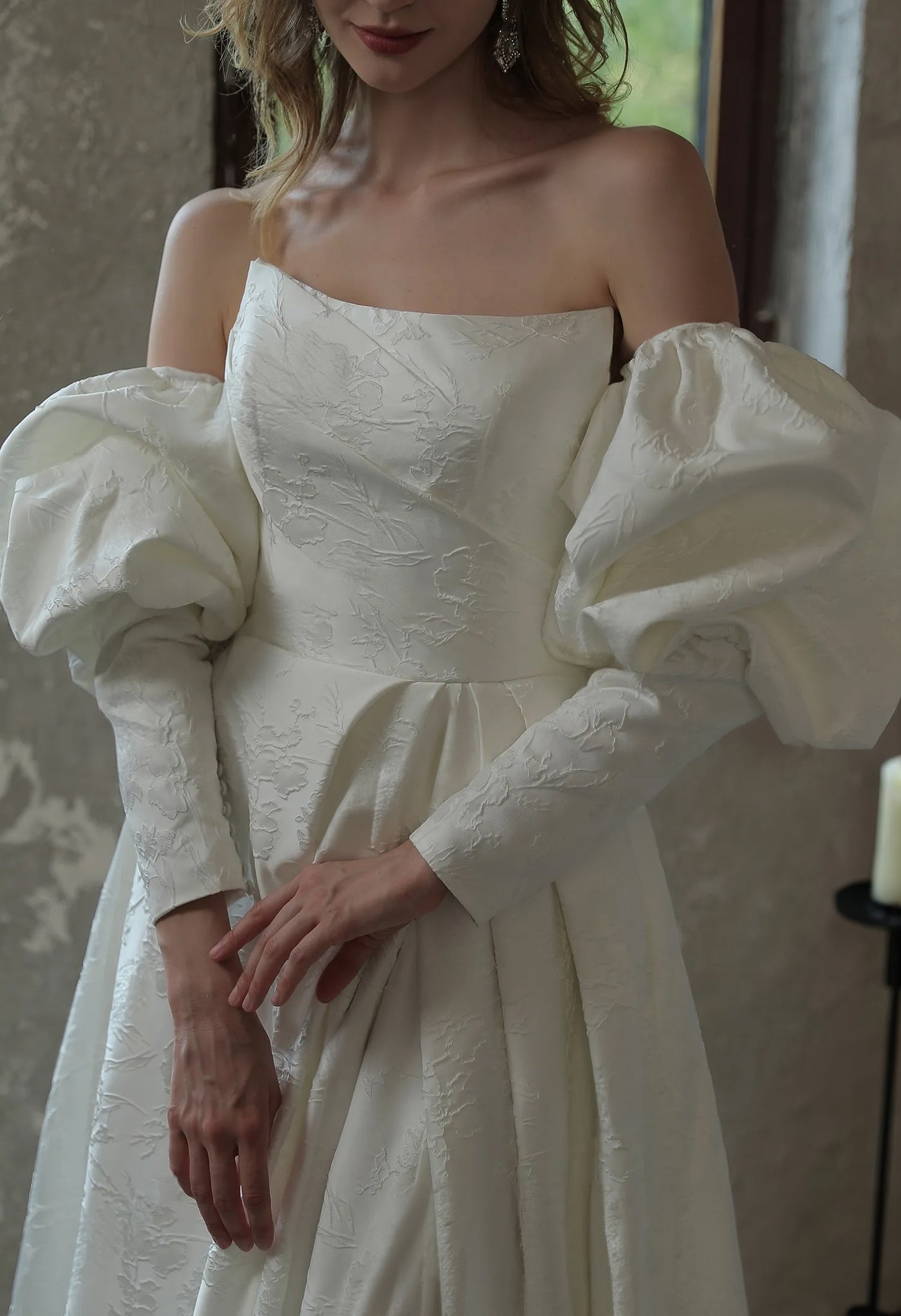 A woman in a white wedding dress posing in front of a window at Bergamot Bridal, wearing the Modern Scoop Neckline Brocade Satin Ball gown.